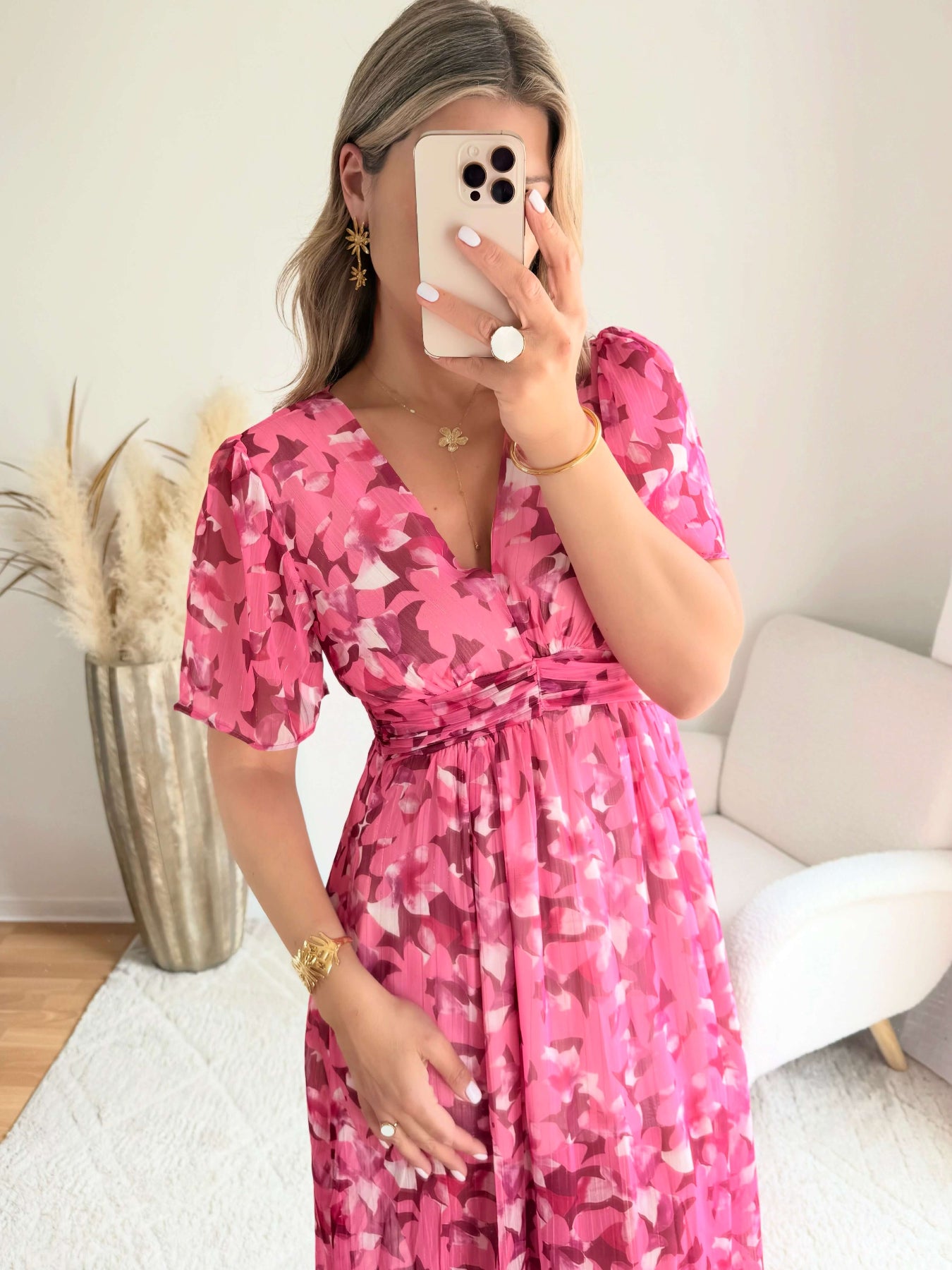 Robe longue plissée rose à imprimé floral avec manches fluides et décolleté croisé.